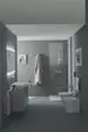 Badezimmerinterieur mit großflächigen grauen Wänden, einem modernen Waschbecken und einer ideal standard Wand-Waschtischarmatur über dem Waschbecken. Dusche mit klaren Wänden sichtbar.